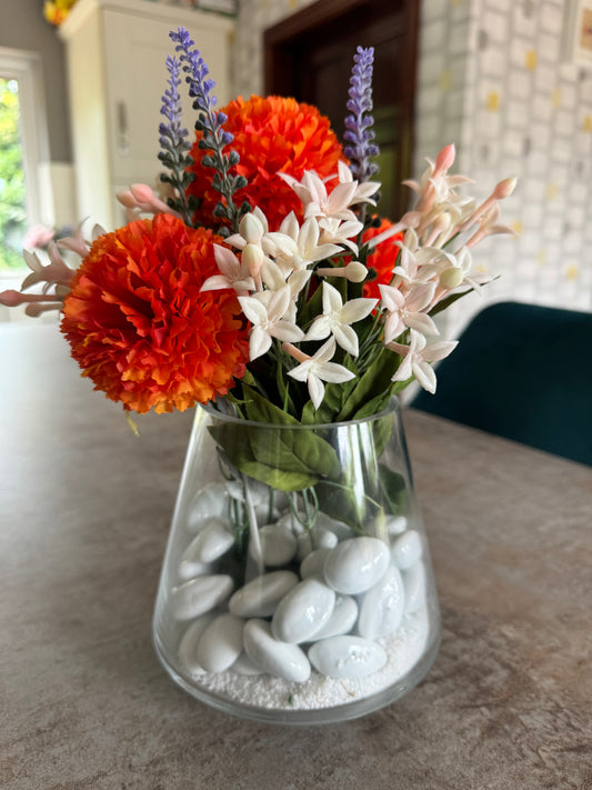 Beautiful orange pom pom flowers with glass vase and rocks