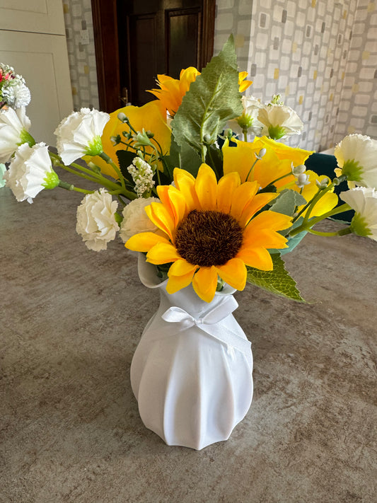 Artificial Sunflowers and yellow roses arrangement in a beautiful white vase